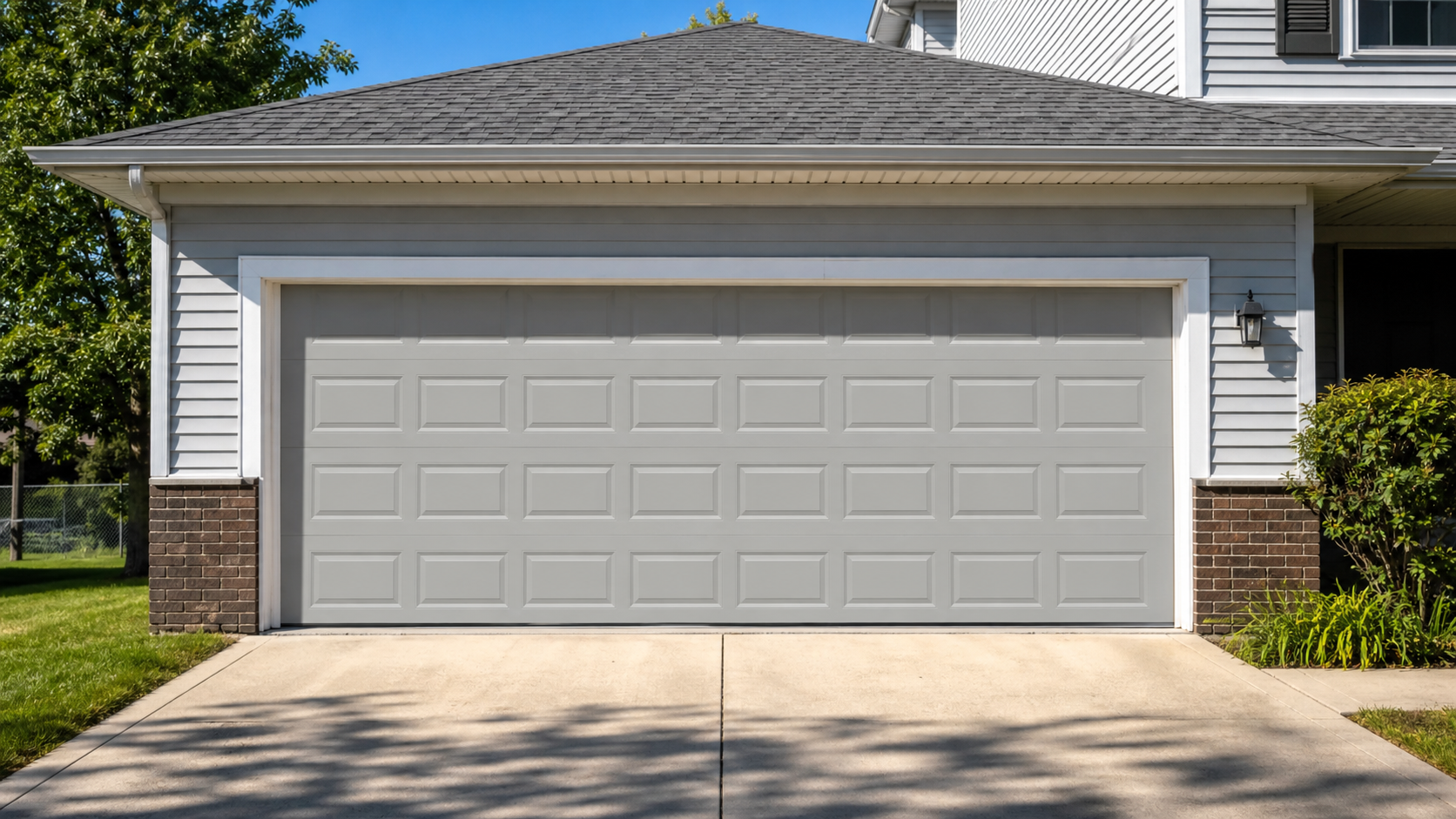 Two-car attached garage with a closed sectional steel door on a Wheeling-area home on a bright summer afternoon
